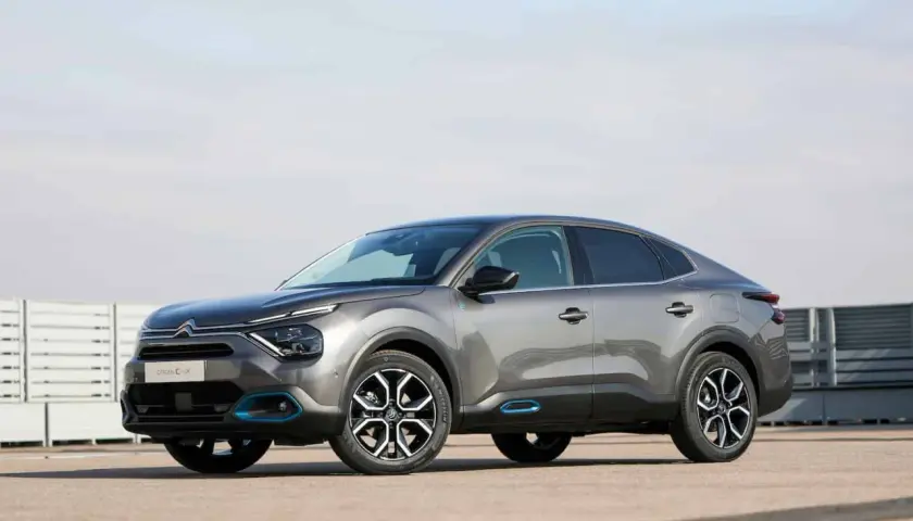 Szary Citroen C4X z niebieskimi akcentami stoi na betonowym placu.