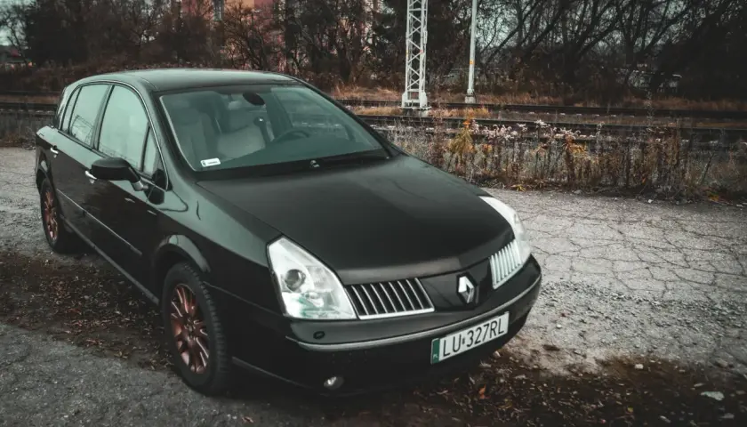 Czarny Renault Vel Satis z miedzianymi felgami stoi przy torach kolejowych.