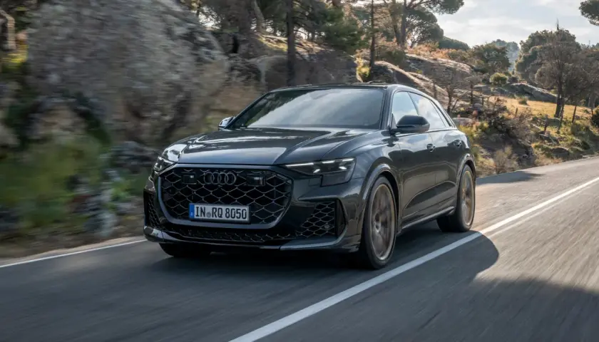 Czarny Audi RS Q8 pędzi po krętej drodze wśród skał i drzew. Sprawdź aktualną audi rsq8 cena!