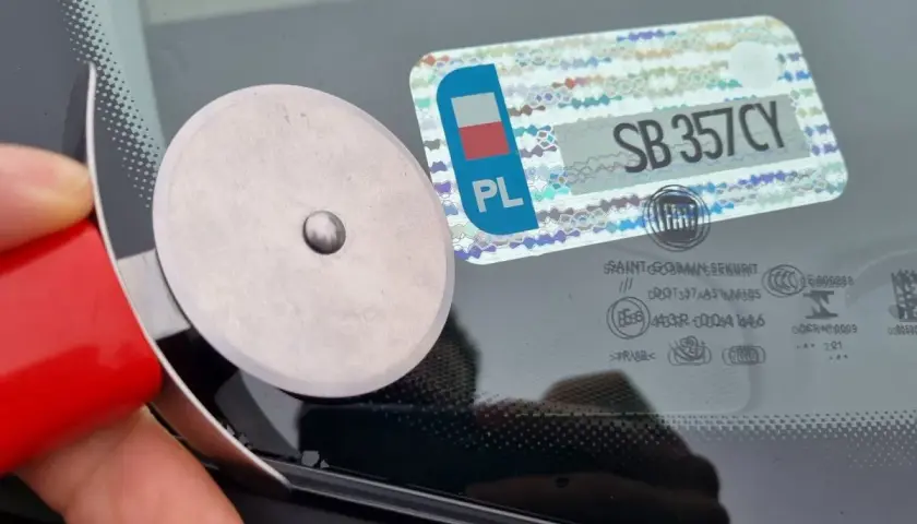 Narzędzie do usuwania naklejek z szyby, obok widoczna polska knt rejestracja SB 357CY.