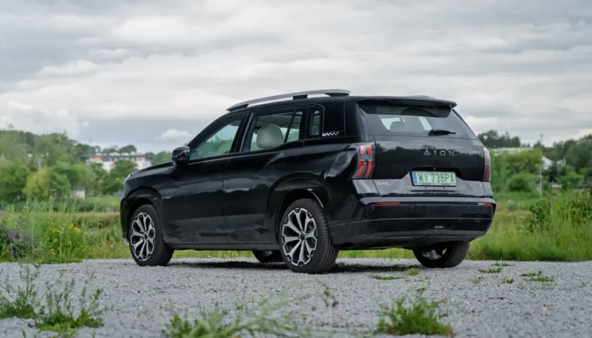 Czarne superauto.pl opinie: GAC Aion V na tle zieleni i chmur.