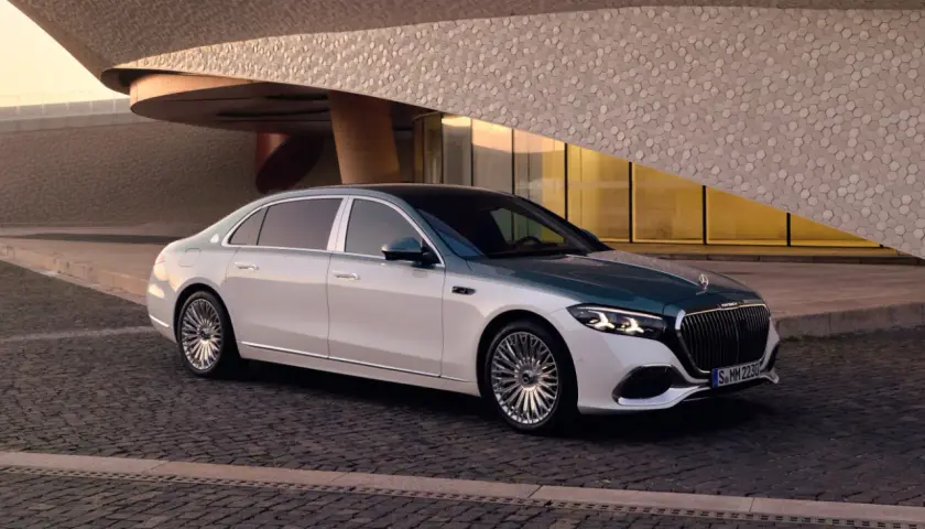 Elegancki Maybach S580 w dwukolorowym malowaniu, zaparkowany przed nowoczesnym budynkiem o geometrycznej fasadzie.