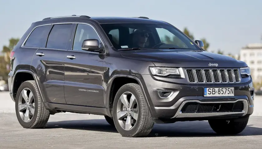 Ciemnoszary Jeep Grand Cherokee WK2 z polskimi tablicami SB 8575N zaparkowany na zewnątrz.