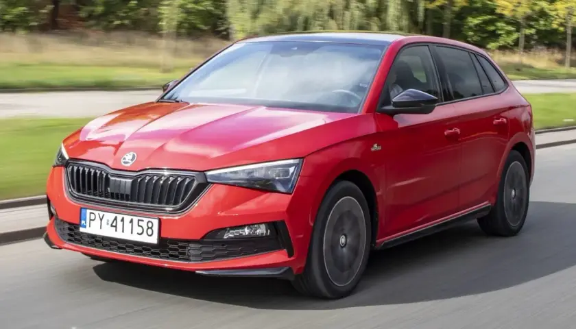 Czerwona Skoda Scala Monte Carlo pędzi po drodze, błyszcząc w słońcu.