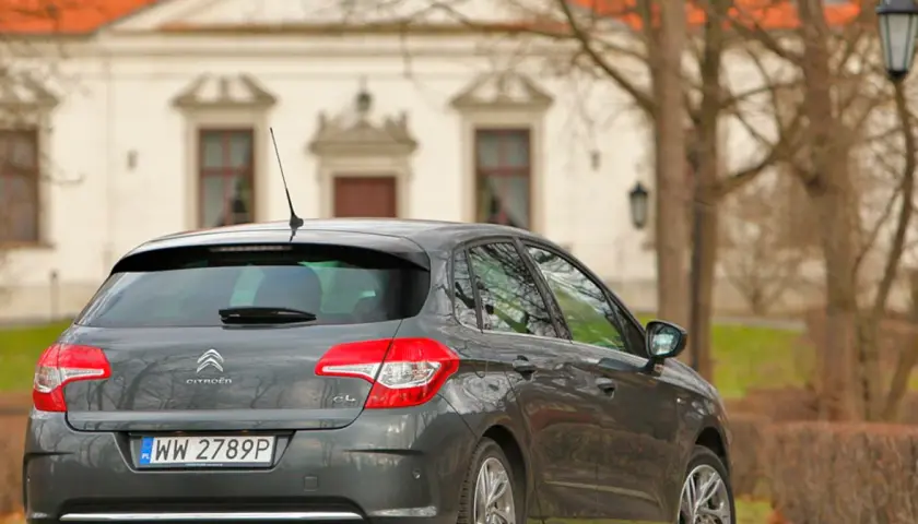 Szary Citroen C4 1.6 HDi zaparkowany przed zabytkowym budynkiem.