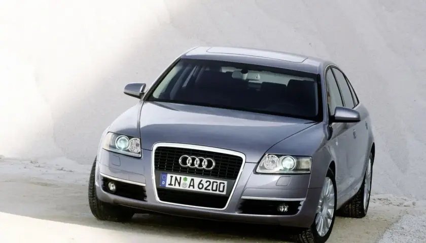 Szary Audi C6 z tablicą rejestracyjną IN A 6200 stoi na piaszczystym podłożu.