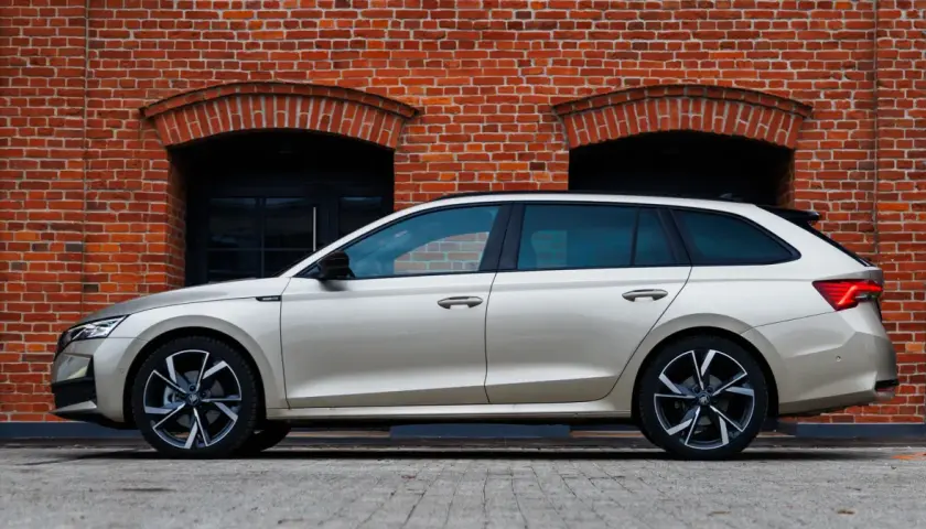 Złoty kombi Octavia 4 stoi na tle ceglanej ściany z dwoma łukowatymi oknami.