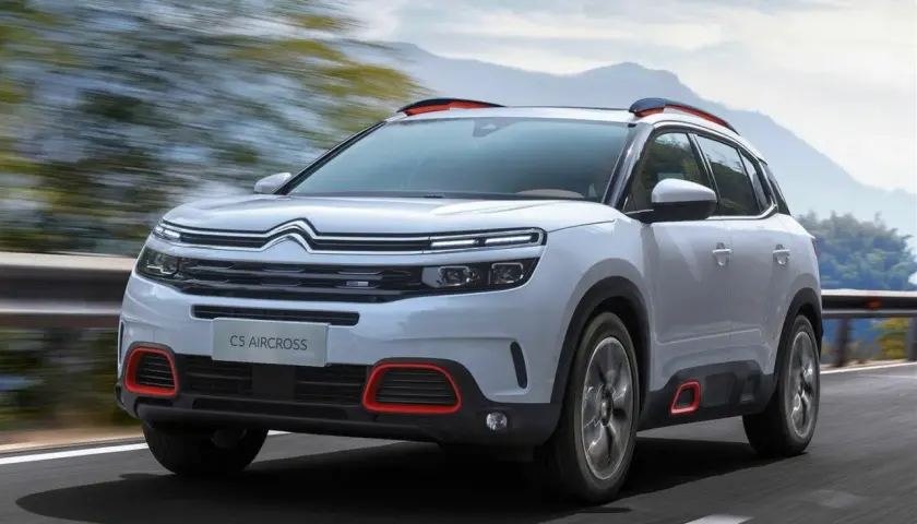 Biały Citroen C5 Aircross z czerwonymi akcentami pędzi po drodze. Wiele osób szuka o nim **citroen c5 aircross opinie**.
