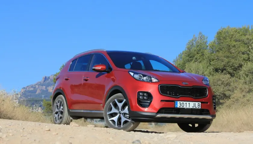 Czerwony Kia Sportage 2008 na tle gór i zieleni, gotowy na przygodę.