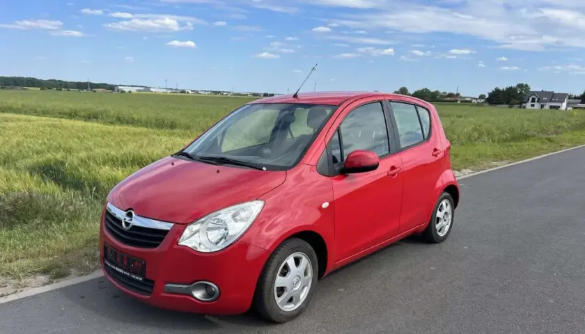 Czerwony Opel Agila 1.2 na tle zielonych pól i błękitnego nieba.
