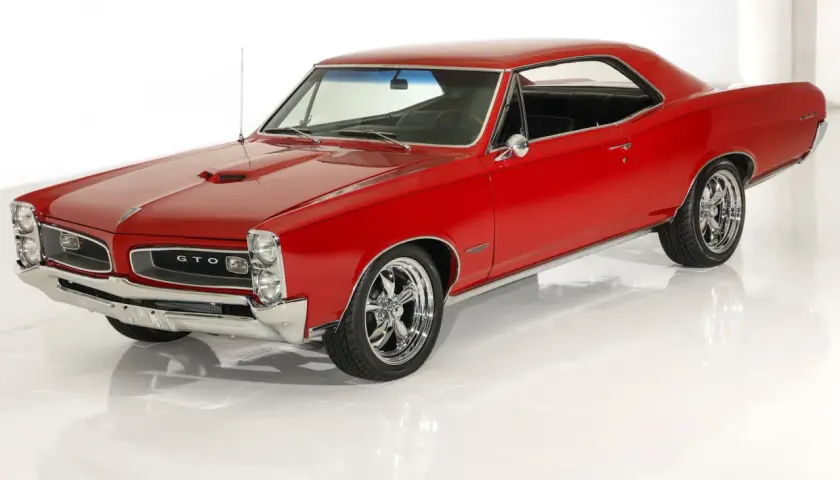Klasyczny, czerwony Pontiac GTO z chromowanymi felgami, lśniącym lakierem i charakterystyczną atrapą chłodnicy.