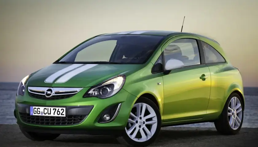 Zielony Opel Corsa D 1.2 benzyna z białymi pasami na masce, zaparkowany na plaży.