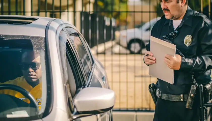 Policjant wręcza kierowcy mandat za spowodowanie kolizji.