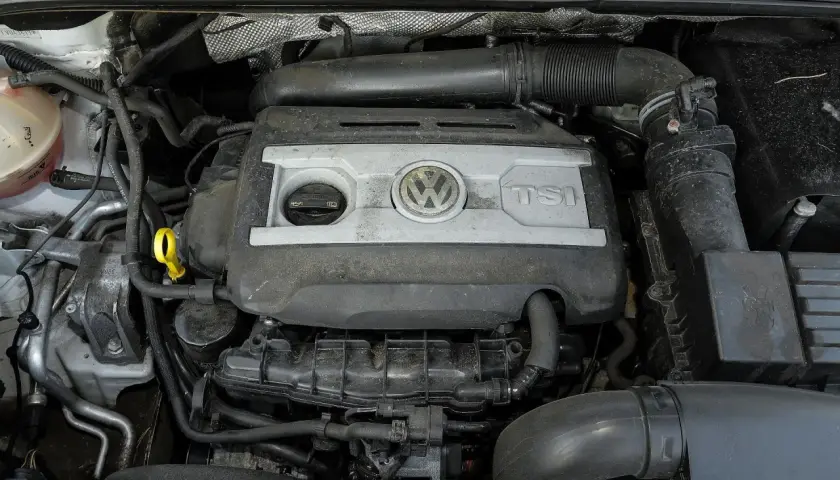 Silnik 2.0 TSI Volkswagena, widok z góry. Widać pokrywę silnika z logo VW i napisem TSI, elementy układu dolotowego i chłodzenia.