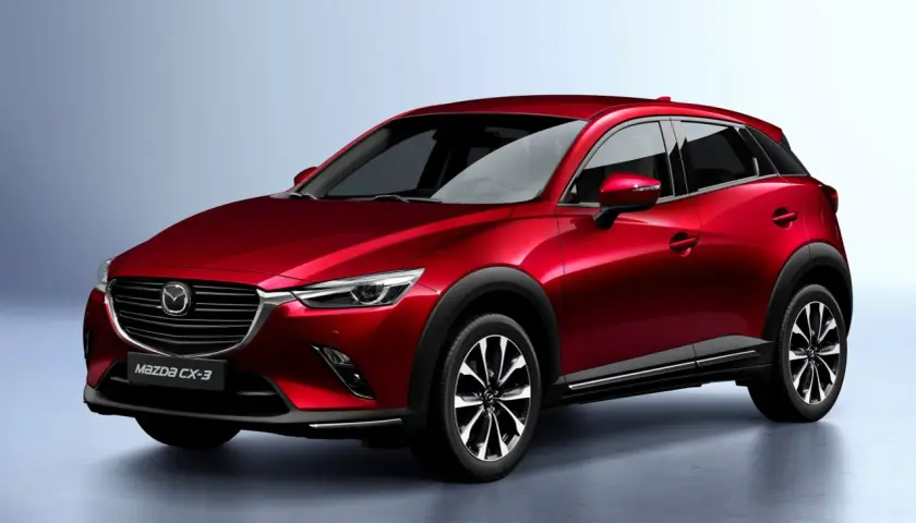 Czerwona Mazda CX-3 na tle jasnoszarego tła. Stylowy crossover, który zbiera pozytywne mazda cx-3 opinie.