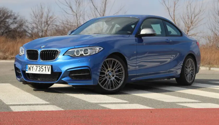 Niebieskie BMW 235i na pasach. Sportowy samochód z charakterystycznym grillem i felgami.