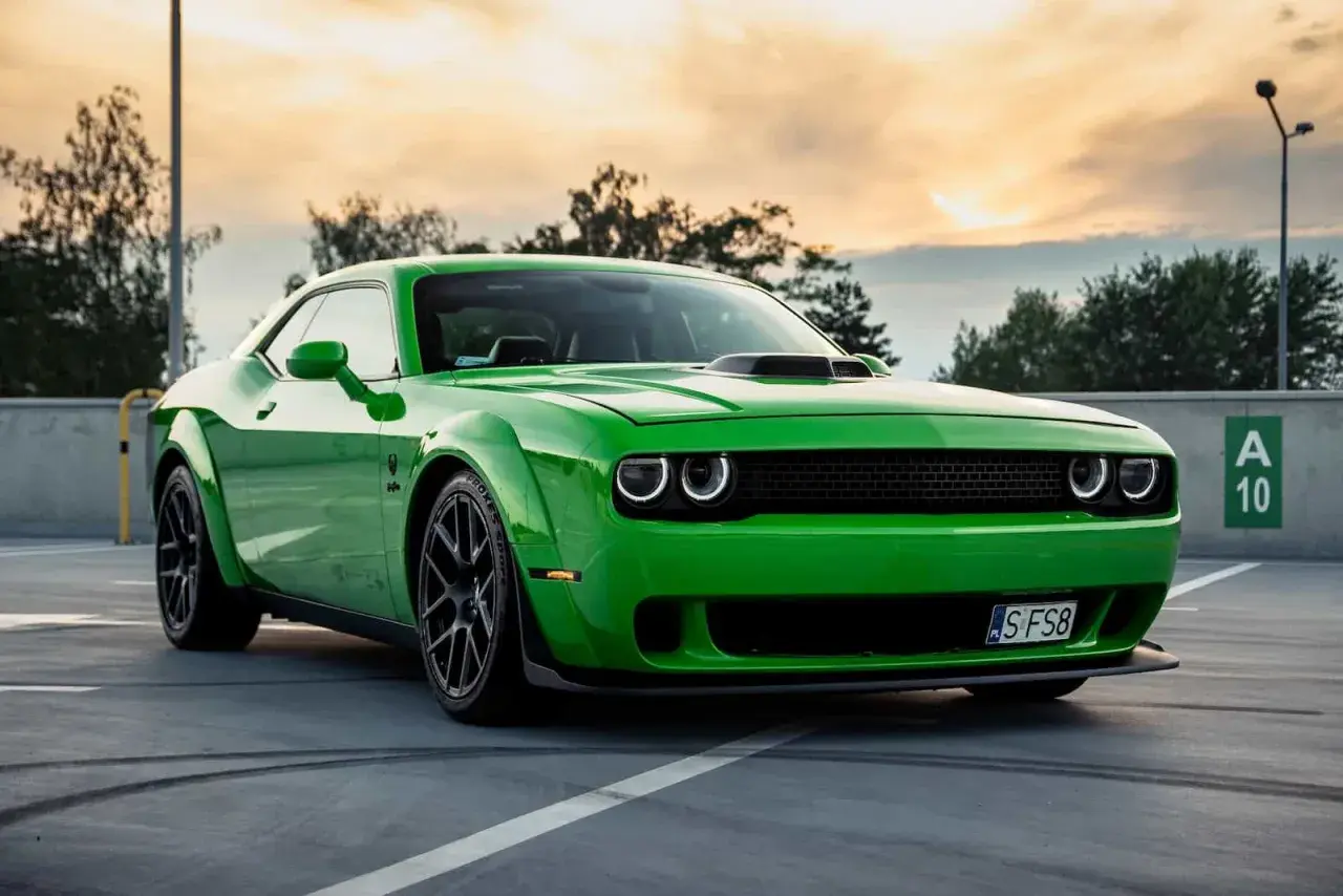 Zielony Dodge Challenger na parkingu. Sprawdź aktualną dodge challenger cena i poczuj moc tego muscle cara.