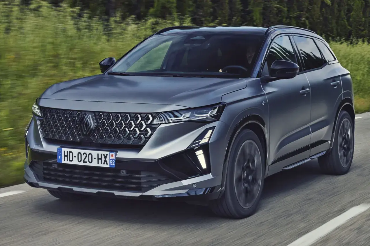 Nowy Austral Renault pędzi po drodze, otoczony zielenią.