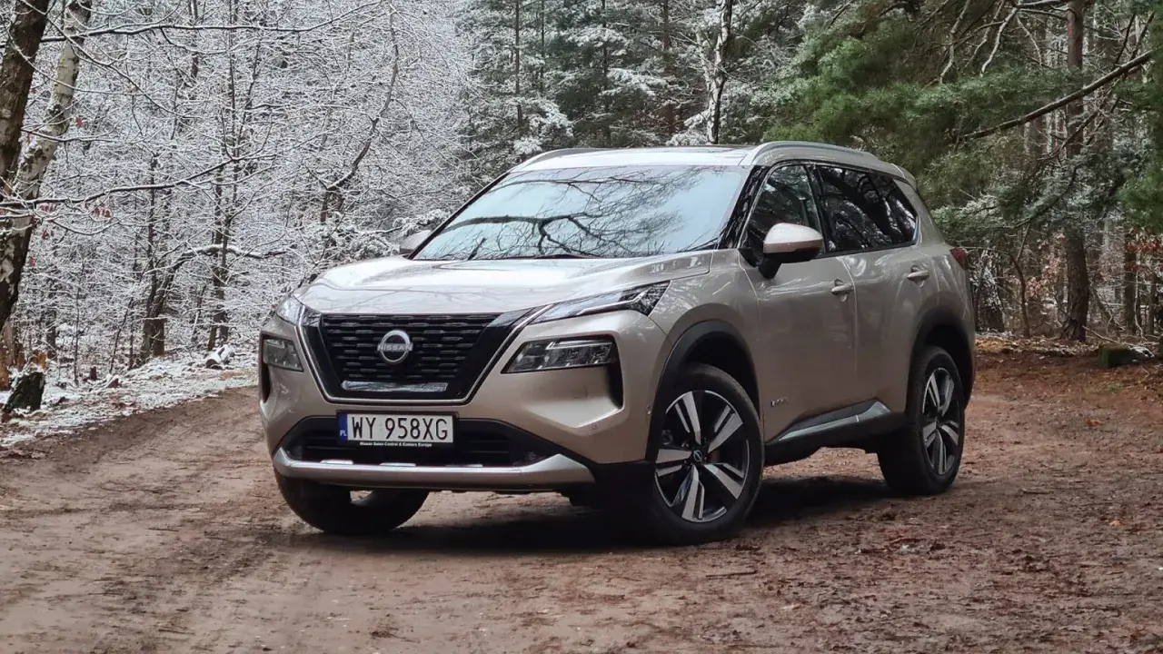 Złoty Nissan X-Trail na leśnej drodze zimą. Wiele osób szuka nissan x trail opinie, ten SUV świetnie radzi sobie w trudnych warunkach.