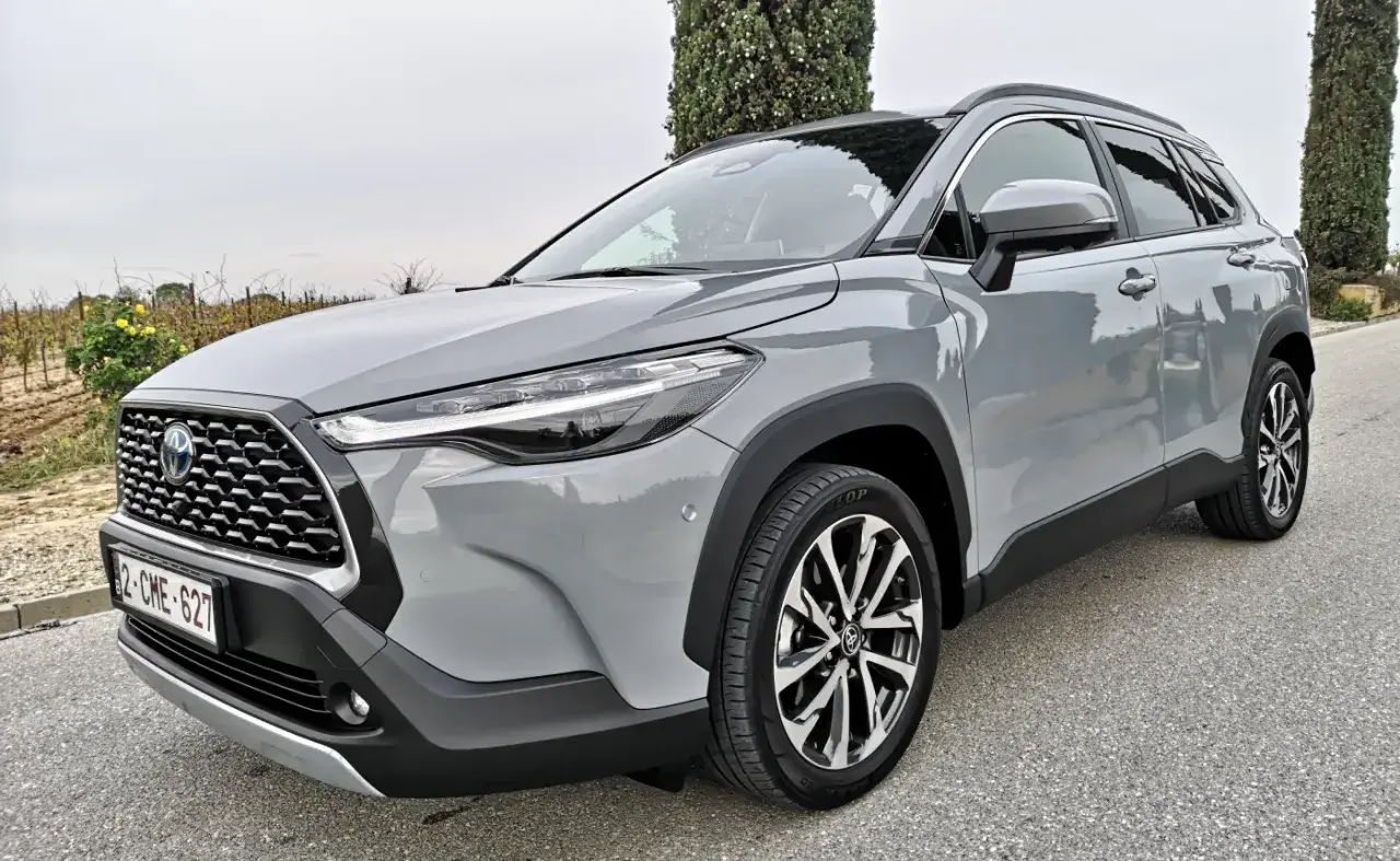 Szary Toyota Corolla SUV stoi na drodze, otoczony zielenią.