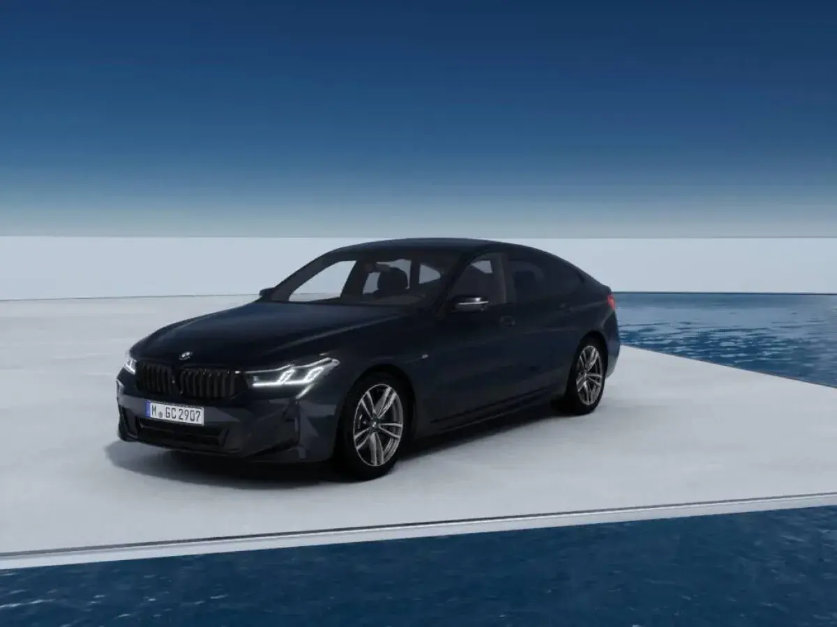 Eleganckie bmw g32 w ciemnym kolorze prezentuje się na platformie nad wodą, z błękitnym niebem w tle.