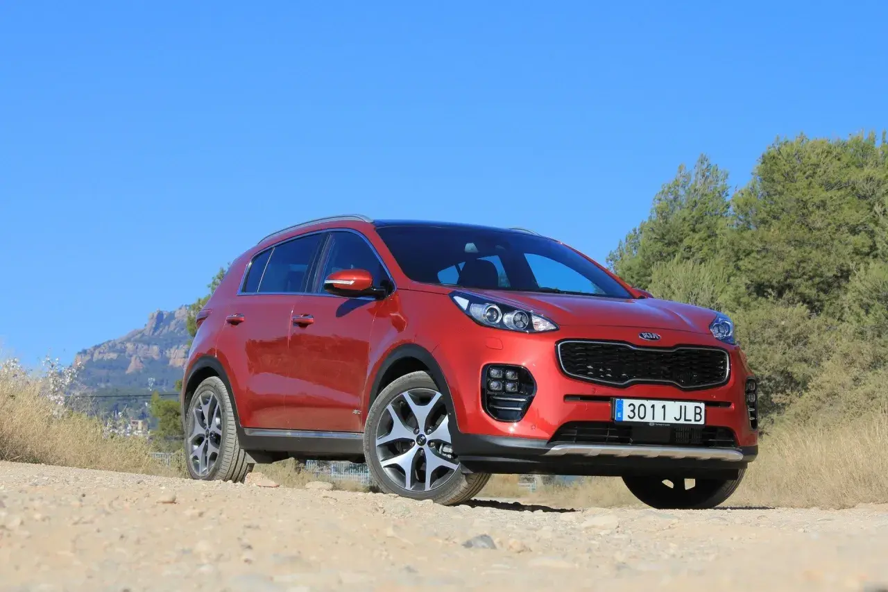 Czerwony Kia Sportage 2008 na tle gór i zieleni, gotowy na przygodę.