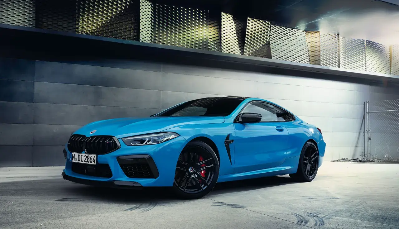 Niebieskie BMW M8 z czarnymi felgami i czerwonymi zaciskami hamulcowymi. Sprawdź aktualną bmw m8 cena.