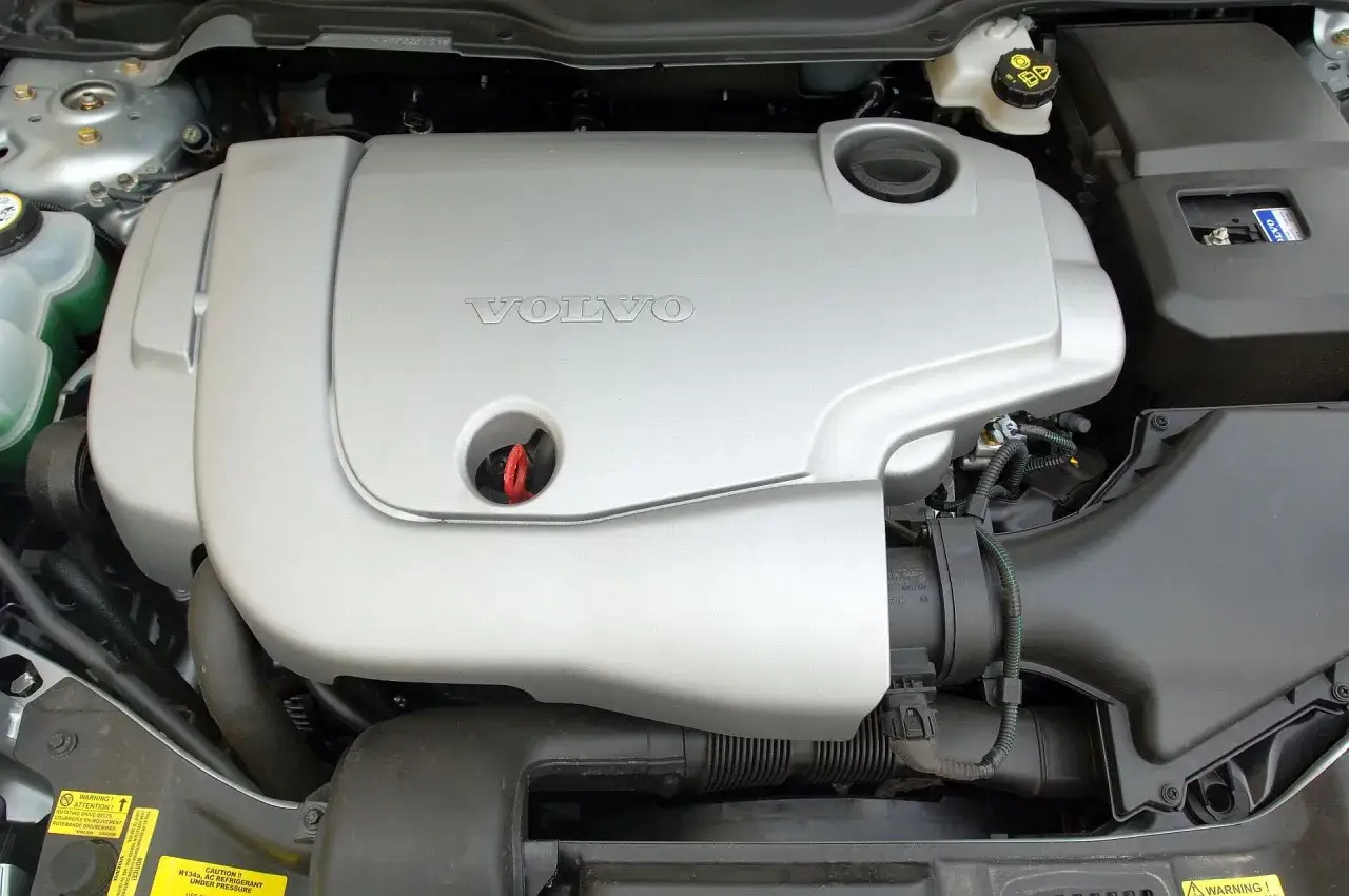 Silnik Volvo V50, często chwalony w volvo v50 opinie, wygląda na zadbany. Widać osłonę silnika z logo Volvo.