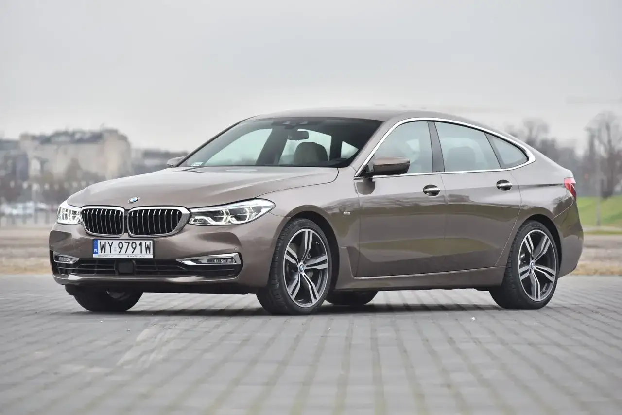Elegancki brązowy BMW G32 na tle miejskiego krajobrazu.