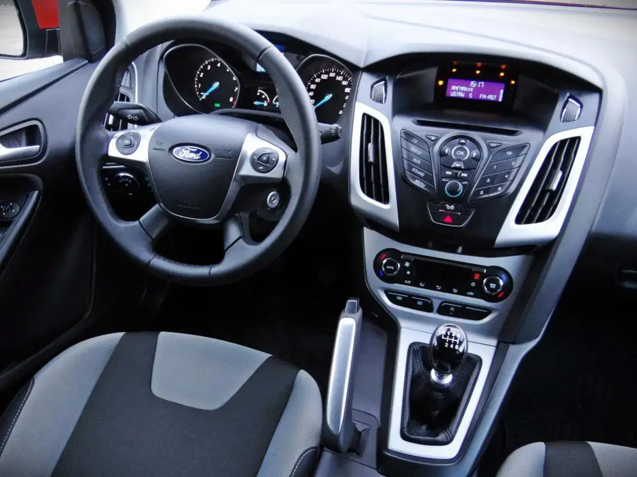 Wnętrze Ford Focus MK3. Kierownica, deska rozdzielcza z radiem i nawiewami, fotel kierowcy. Wiele osób chwali ten model, a ford focus mk3 opinie są zazwyczaj pozytywne.
