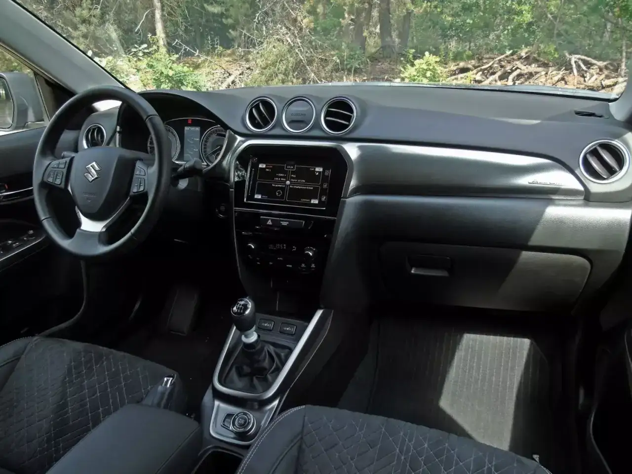 Wnętrze Suzuki Vitara 2025: kierownica, ekran multimedialny, dźwignia zmiany biegów i fotele.