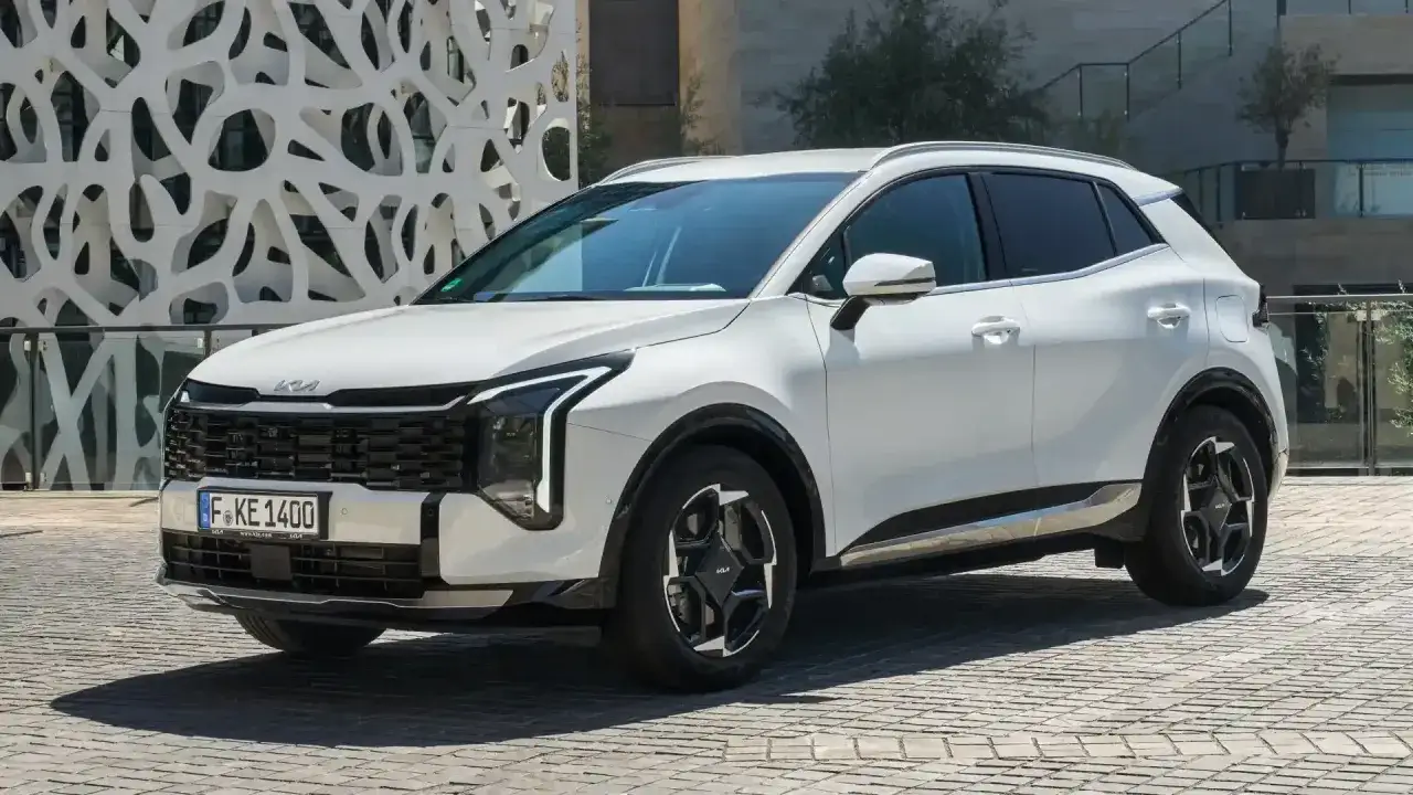 Biały Kia Sportage 2008 z nowoczesnym designem, zaparkowany przed budynkiem o ciekawej architekturze.