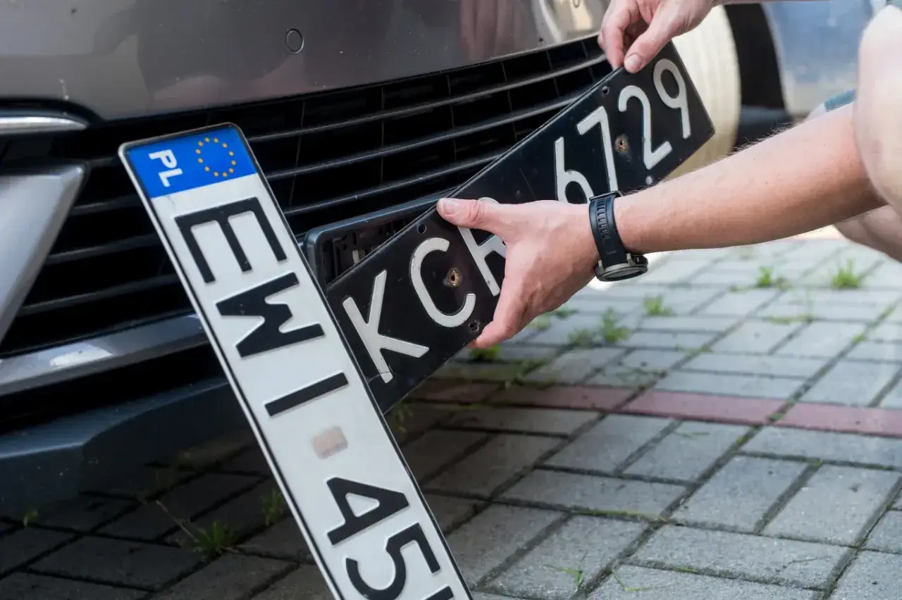 Ręce montują tablicę rejestracyjną. Nowe tablice to ważny etap ep rejestracja.