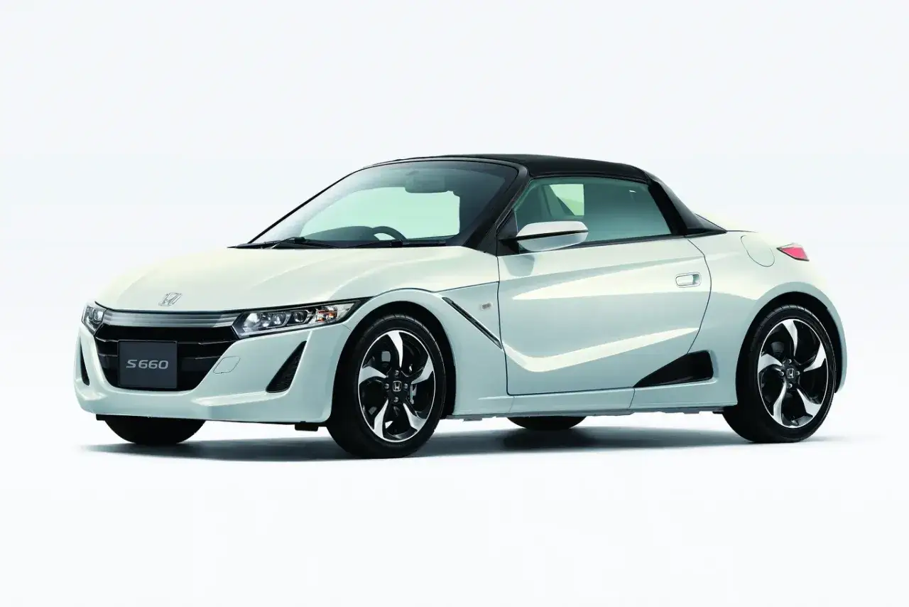 Biały kabriolet Honda S660 z czarnym dachem, sportowymi felgami i agresywnym przodem.