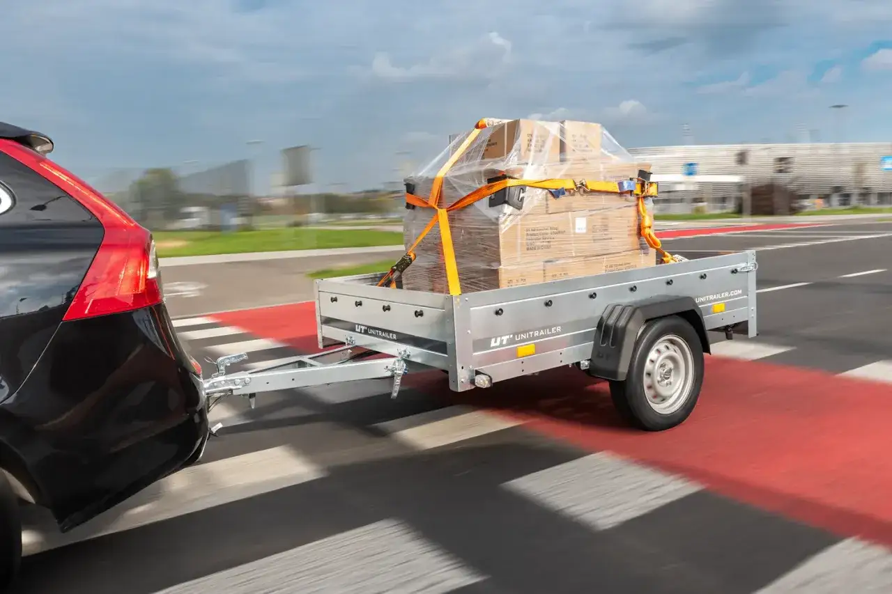 Samochód ciągnie przyczepę z zapakowanym towarem. Posiadanie prawa jazdy na przyczepę to klucz do bezpiecznego transportu.