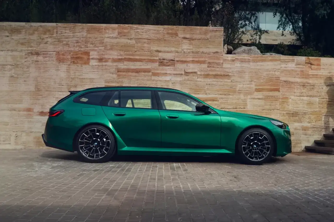 Zielone BMW M5 kombi na tle kamiennej ściany. Sprawdź aktualną bmw m5 cena.