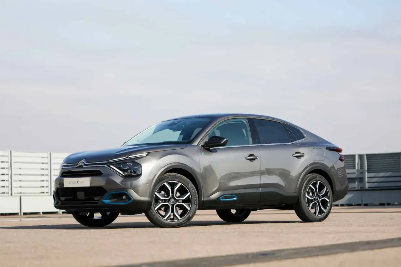 Szary Citroen C4X z niebieskimi akcentami stoi na tle jasnego nieba.