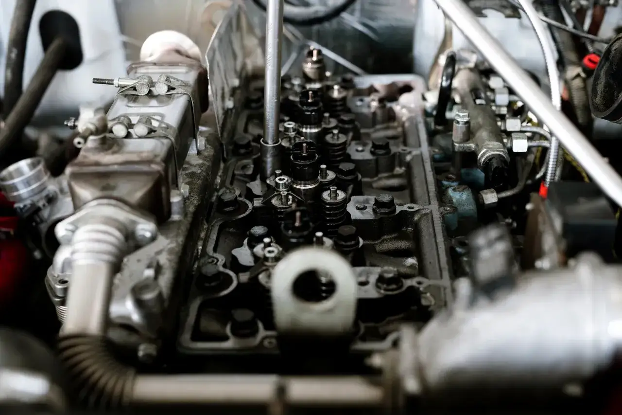 Wnętrze silnika z widocznymi zaworami i wtryskiwaczami. Mechanik sprawdza, czy nie występuje spalanie stukowe.