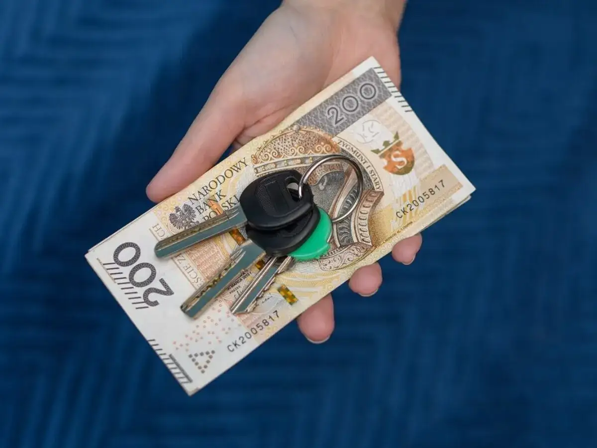Dłoń trzyma banknot 200 zł i klucze. Zastanawiasz się, ile kosztuje własna rejestracja?