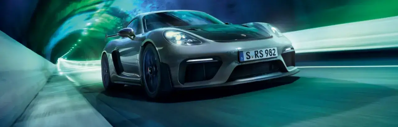 Porsche GT4 RS pędzi przez tunel, otoczony zielonymi i niebieskimi światłami, tworząc dynamiczną scenę.