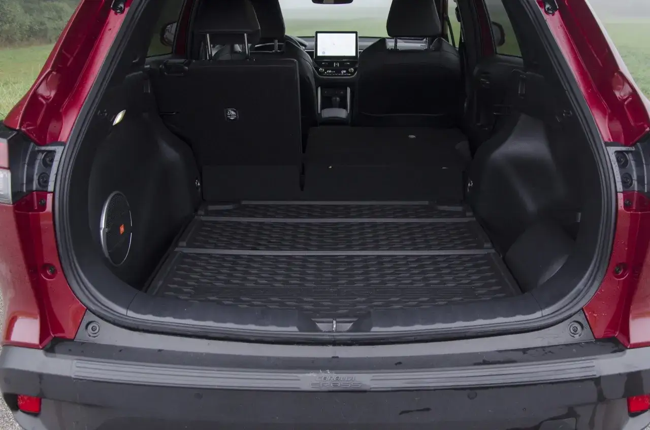 Bagażnik czerwonego toyota corolla suv z podniesioną klapą. Widać gumową matę, głośnik JBL i złożone tylne siedzenia.