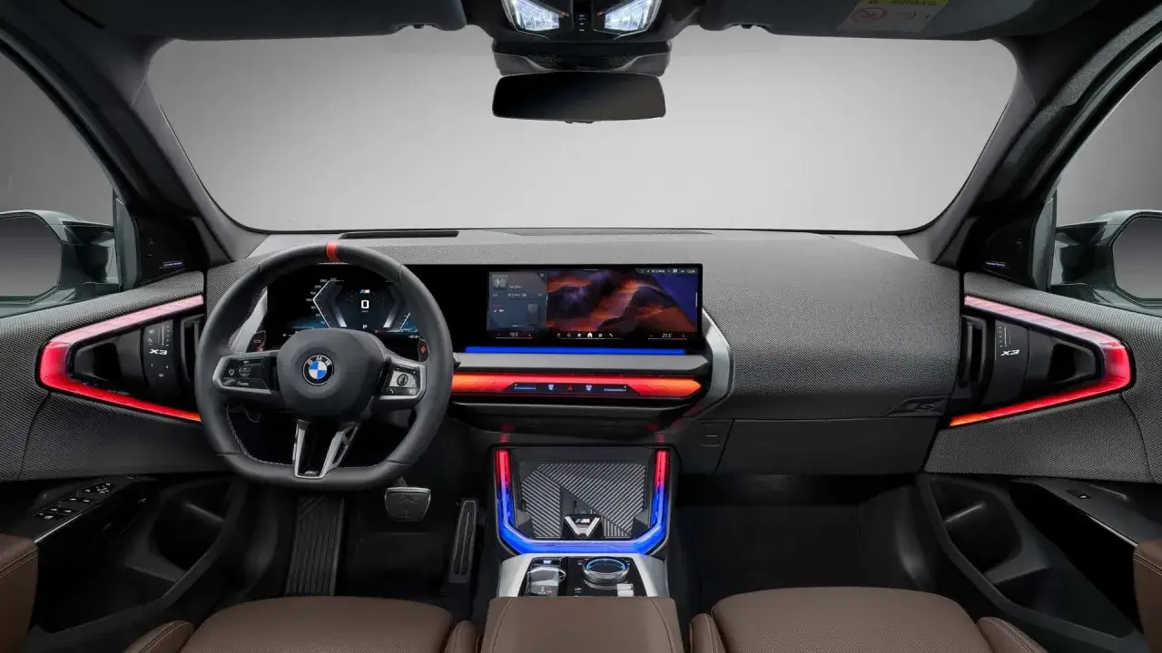 Wnętrze x3 bmw z nowoczesnym ekranem, podświetleniem ambientowym i sportową kierownicą.