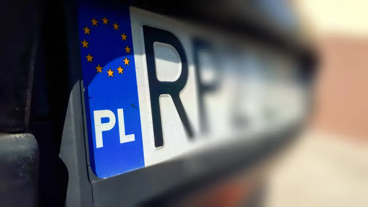 Zbliżenie na polską tablicę rejestracyjną z symbolem UE. Litery 