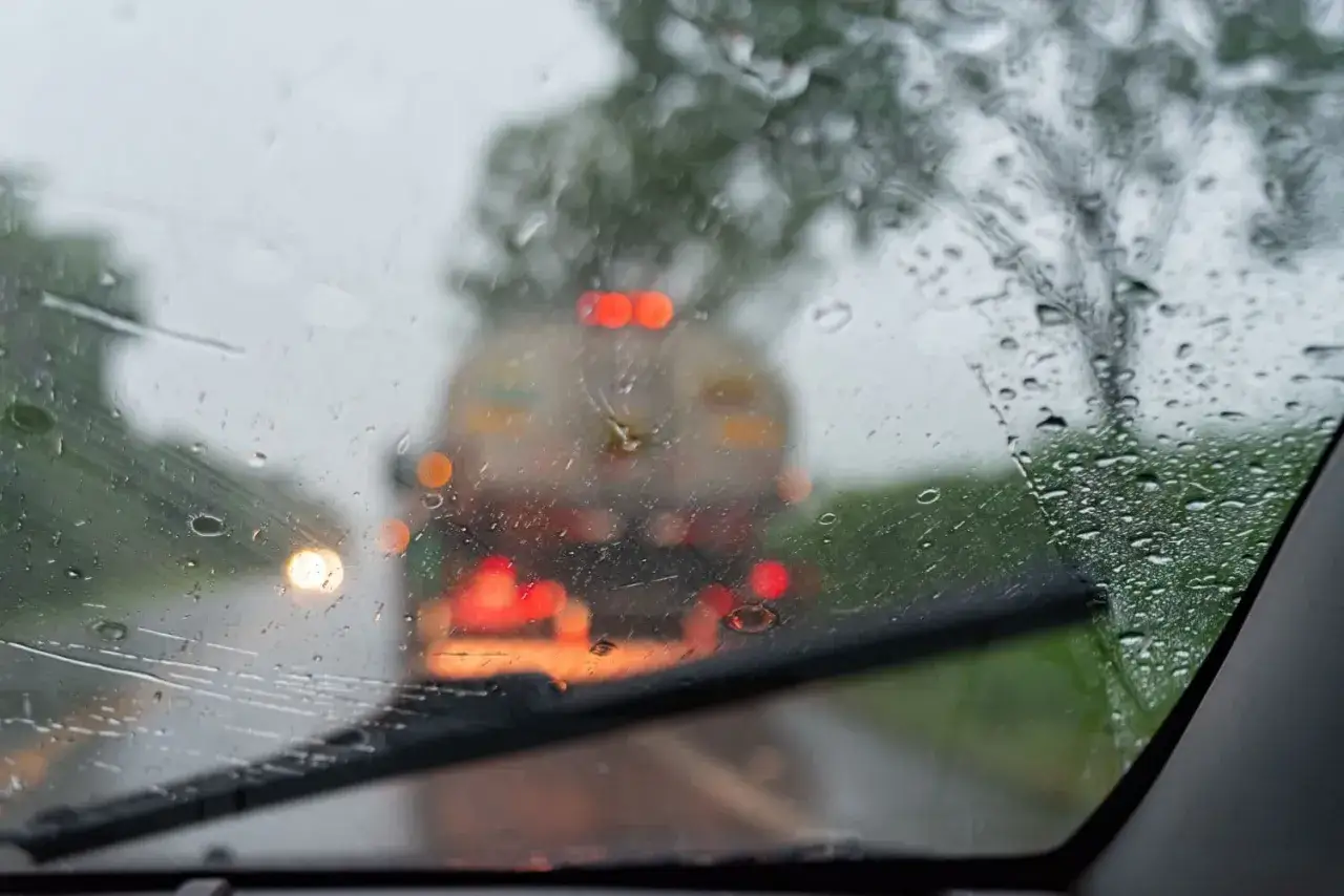 Widok zza zaparowanej szyby przedniej w deszczu. Zbliża się ciężarówka. Czas pomyśleć o wymiana szyby przedniej cena.