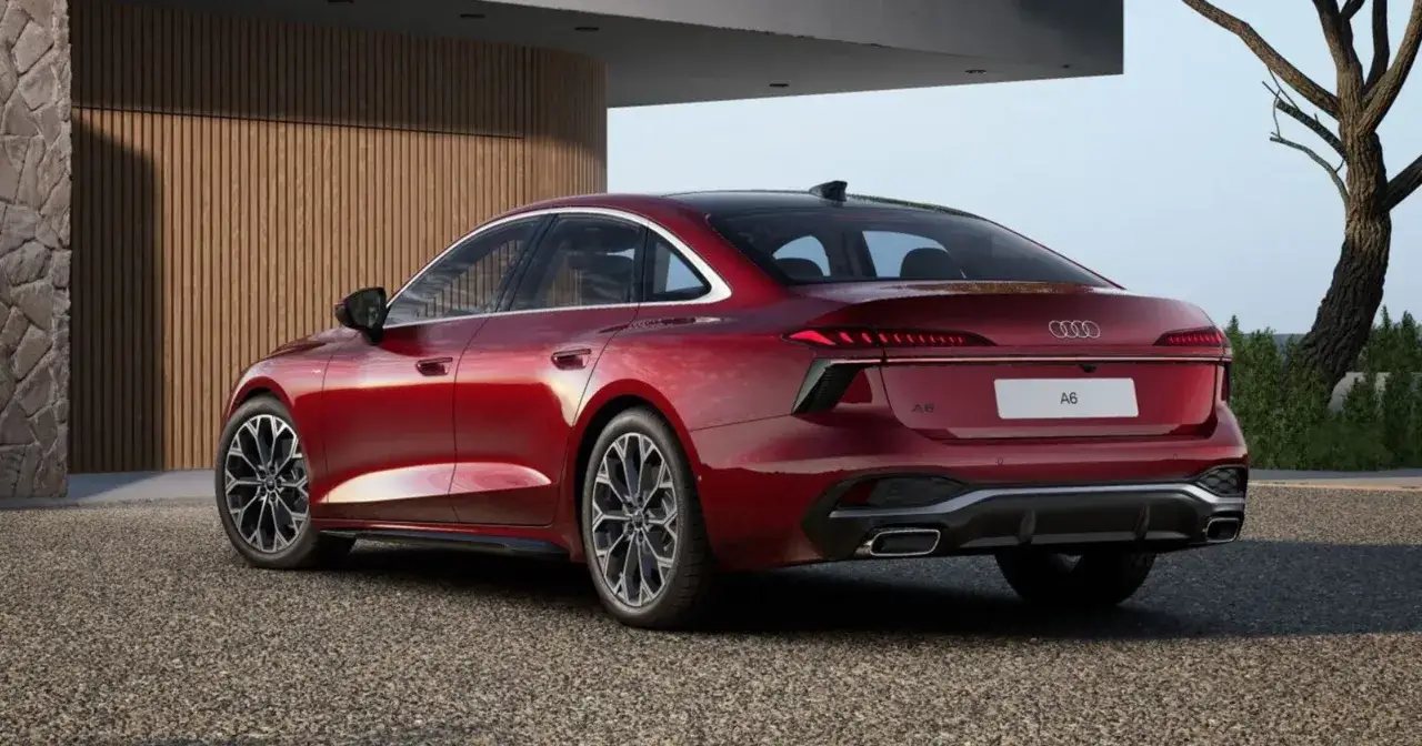 Eleganckie Audi A6 w kolorze wiśniowym, zaparkowane przed nowoczesnym budynkiem. Sprawdź aktualną audi a6 cena i dostępne konfiguracje.