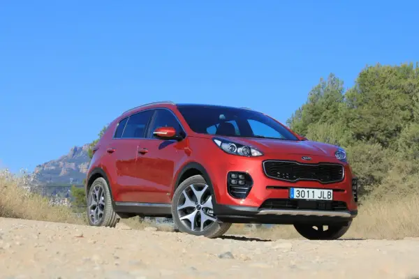 Czerwony Kia Sportage 2008 na tle gór i zieleni, gotowy na przygodę.
